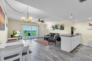 Ein modernes Wohnzimmer mit Essbereich, einer Kücheninsel und einem Balkon mit Blick.