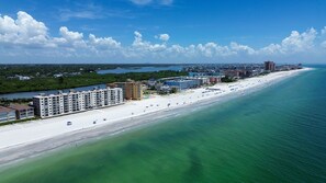 An aerial view of a coastal area with a beach, buildings, and a body of water.