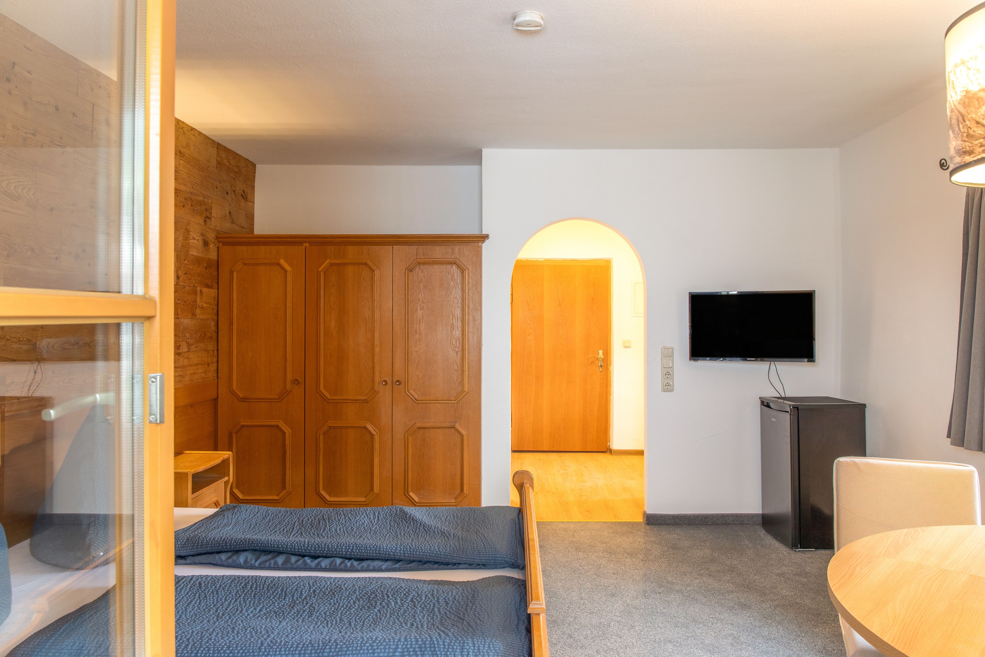 Ein Hotelzimmer mit Bett, Fernseher, Schrank und Schreibtisch.