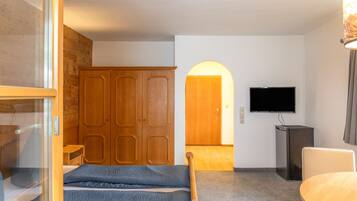 Ein Hotelzimmer mit Bett, Fernseher, Schrank und Schreibtisch.