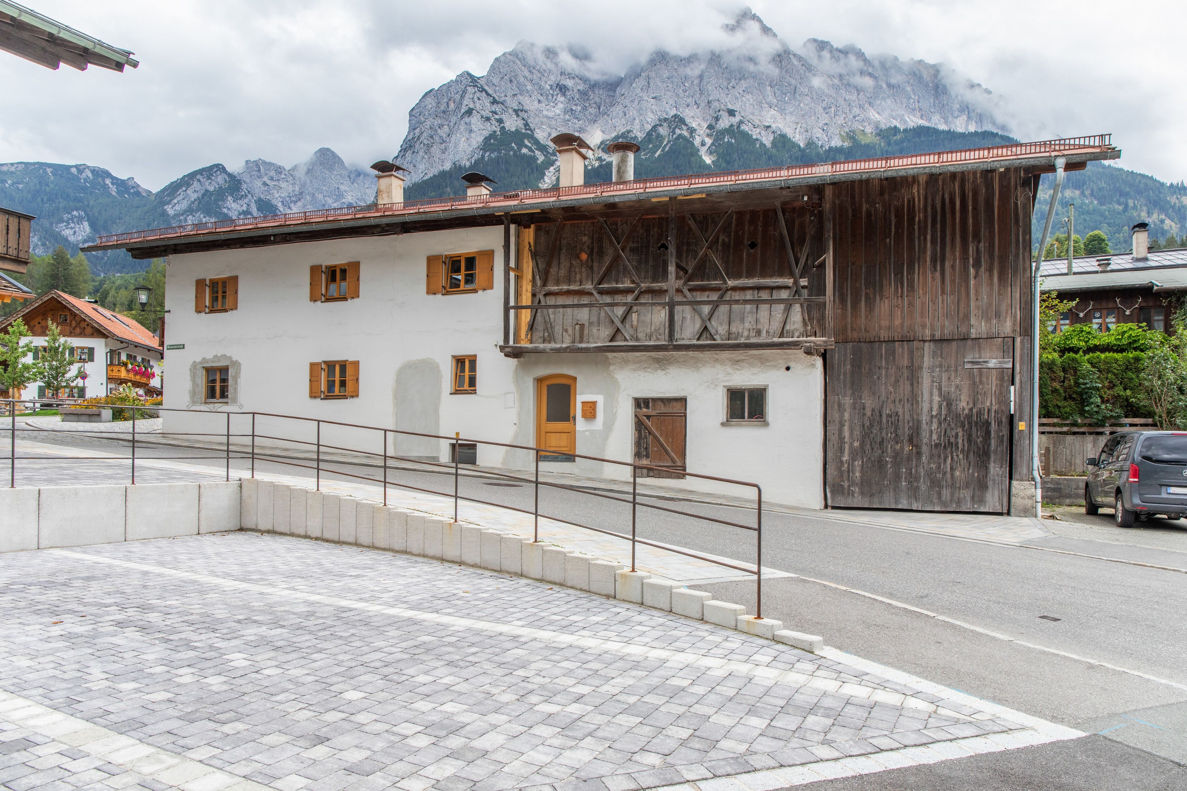 Ein Gebäude mit einer Holzfassade, einem Balkon und Blick auf Berge im Hintergrund.