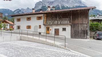 Ein Gebäude mit einer Holzfassade, einem Balkon und Blick auf Berge im Hintergrund.