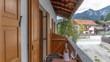 Varanda de madeira com mesa e cadeiras, com vista para uma paisagem montanhosa.