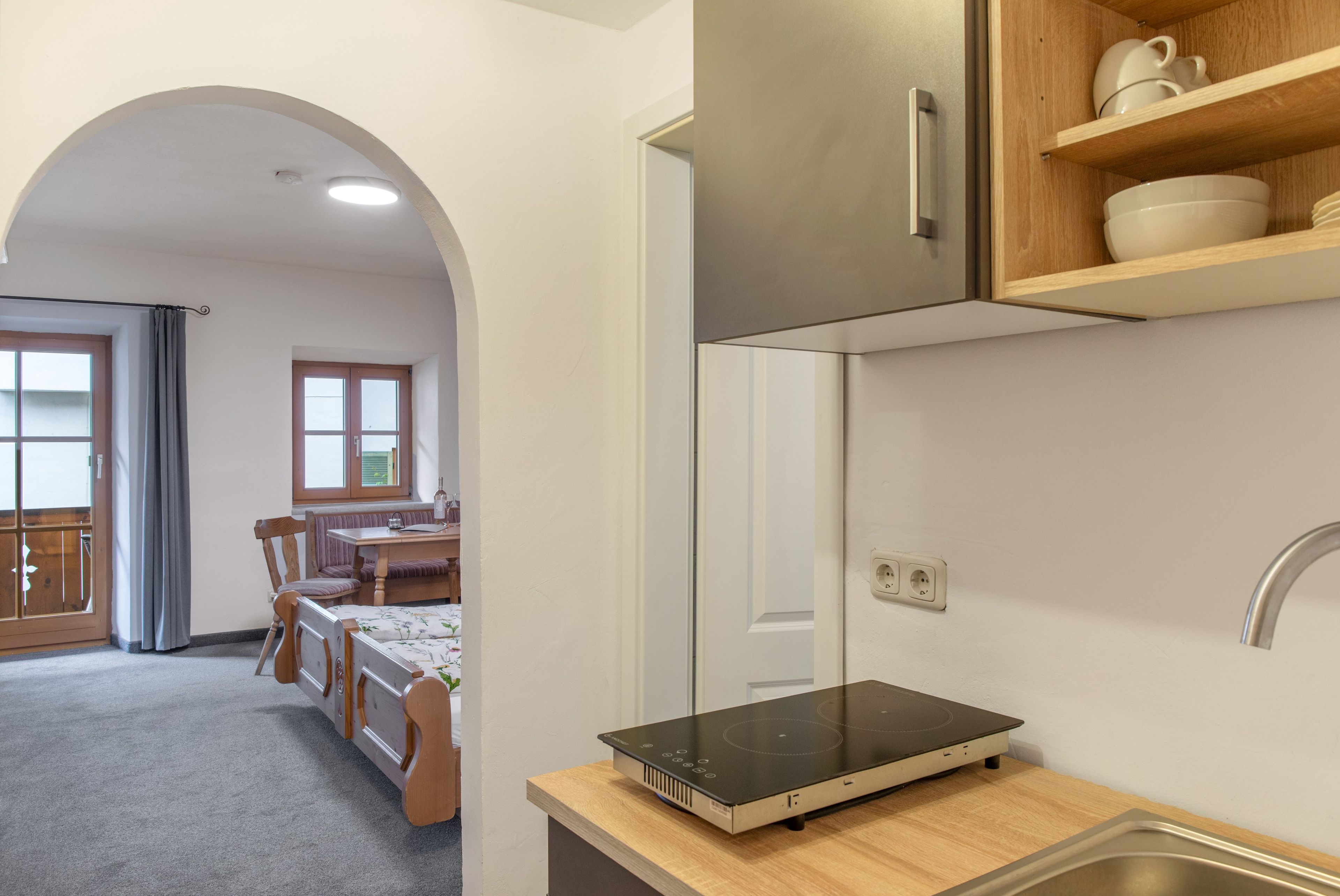 A kitchen with a built-in induction cooktop, wooden cabinets, and a stainless steel sink.