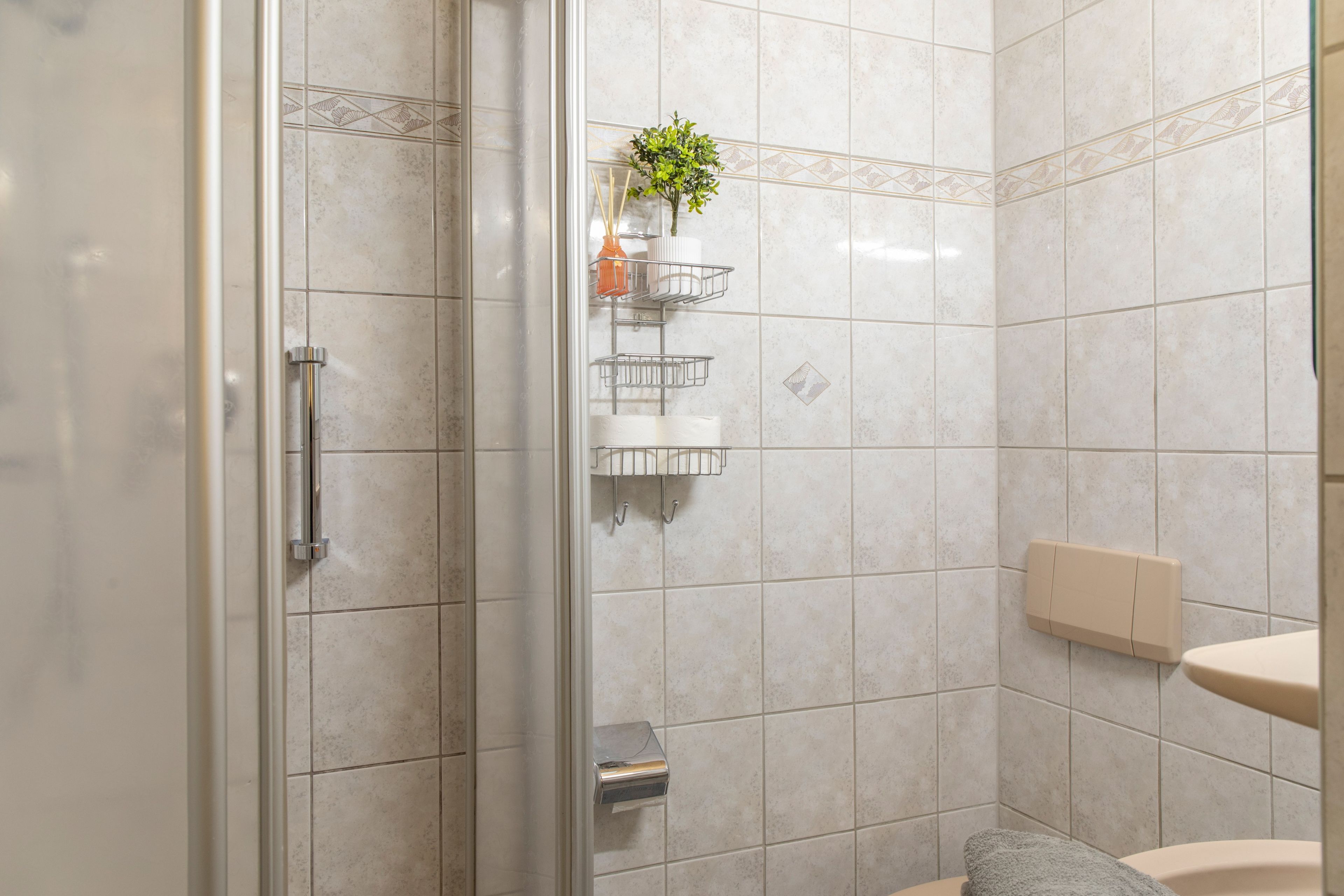 Un bagno con cabina doccia in vetro, un water, un lavandino e un portasciugamani.