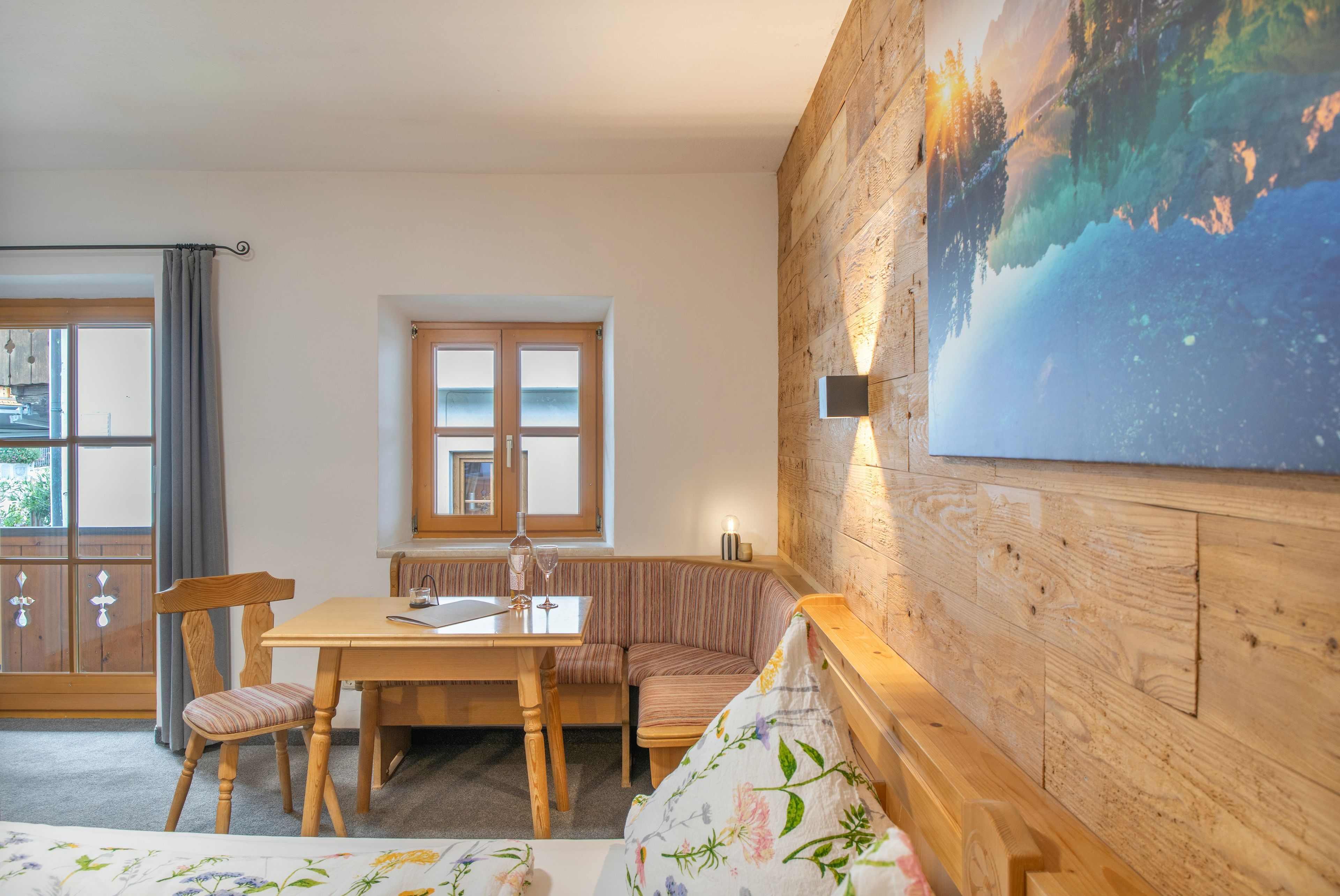 Una habitación acogedora con una pared de madera, una mesa de comedor, un banco y un ventanal grande.