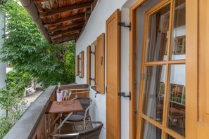 Un balcone con tavolo e sedie, una bottiglia e dei bicchieri.