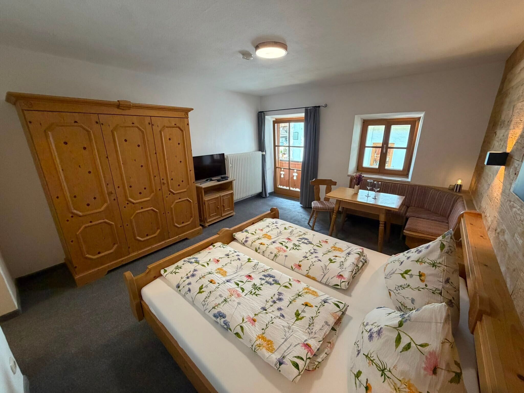 Un dormitorio con dos camas, un armario de madera, un televisor, una mesa y una ventana.