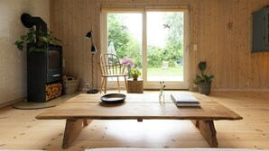 Ett rum med ett träbord, en stol, en öppen spis och utsikt över naturen.
