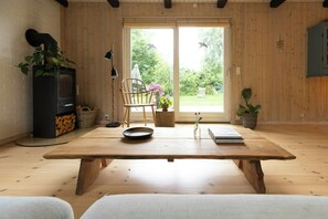 A room with a wooden table, a chair, a fireplace, and a view of the outdoors. - Holiday home with enchanting garden in Kulhuse (Jægerspris)