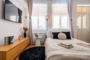 Ein modernes Schlafzimmer mit einem Bett, einem Nachttisch und einem an der Wand befestigten Fernseher.