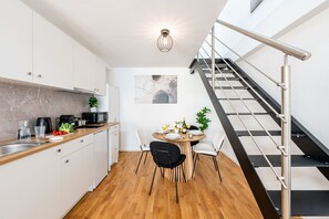 A modern kitchen with white cabinets, a wooden countertop, and a dining area with a round table and chairs. - New Town City Loft with Free Parking (Prague)