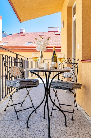A balcony with a table set for two, featuring a vase with flowers, a candle, and a bottle of wine. - New Town City Loft with Free Parking (Prague)