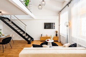 Ein modernes Wohnzimmer mit Treppe, Essbereich und großem Fenster.