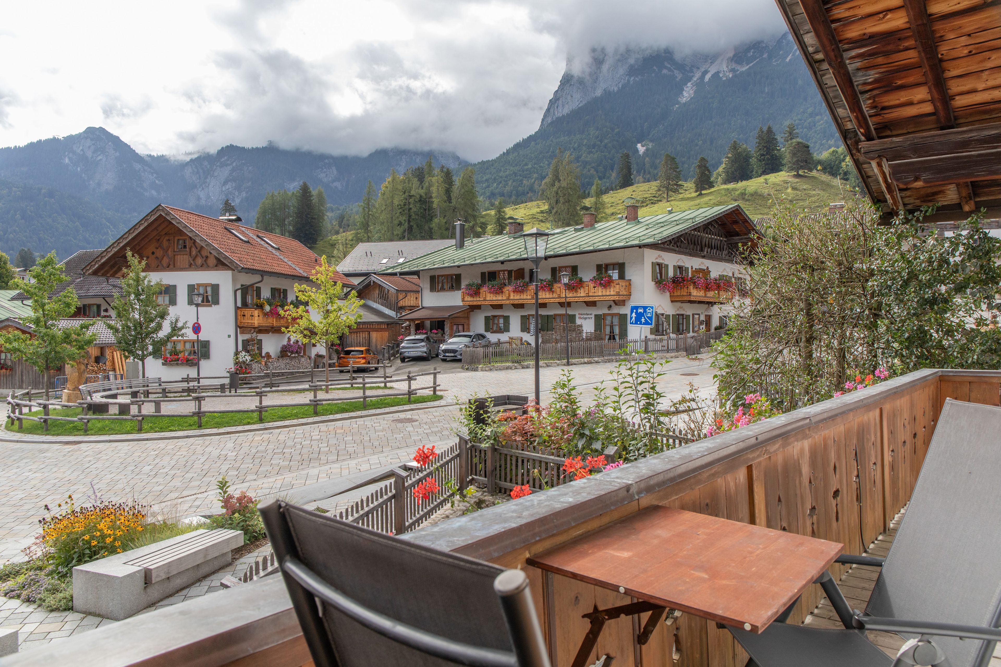 Blick auf Berge mit traditionellen Holzbauten, einer gepflasterten Straße und einem Restaurant mit Außenbereich.