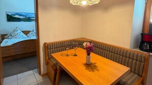 Un comedor con una mesa de madera y bancos, una lámpara colgante y un cuadro en la pared.