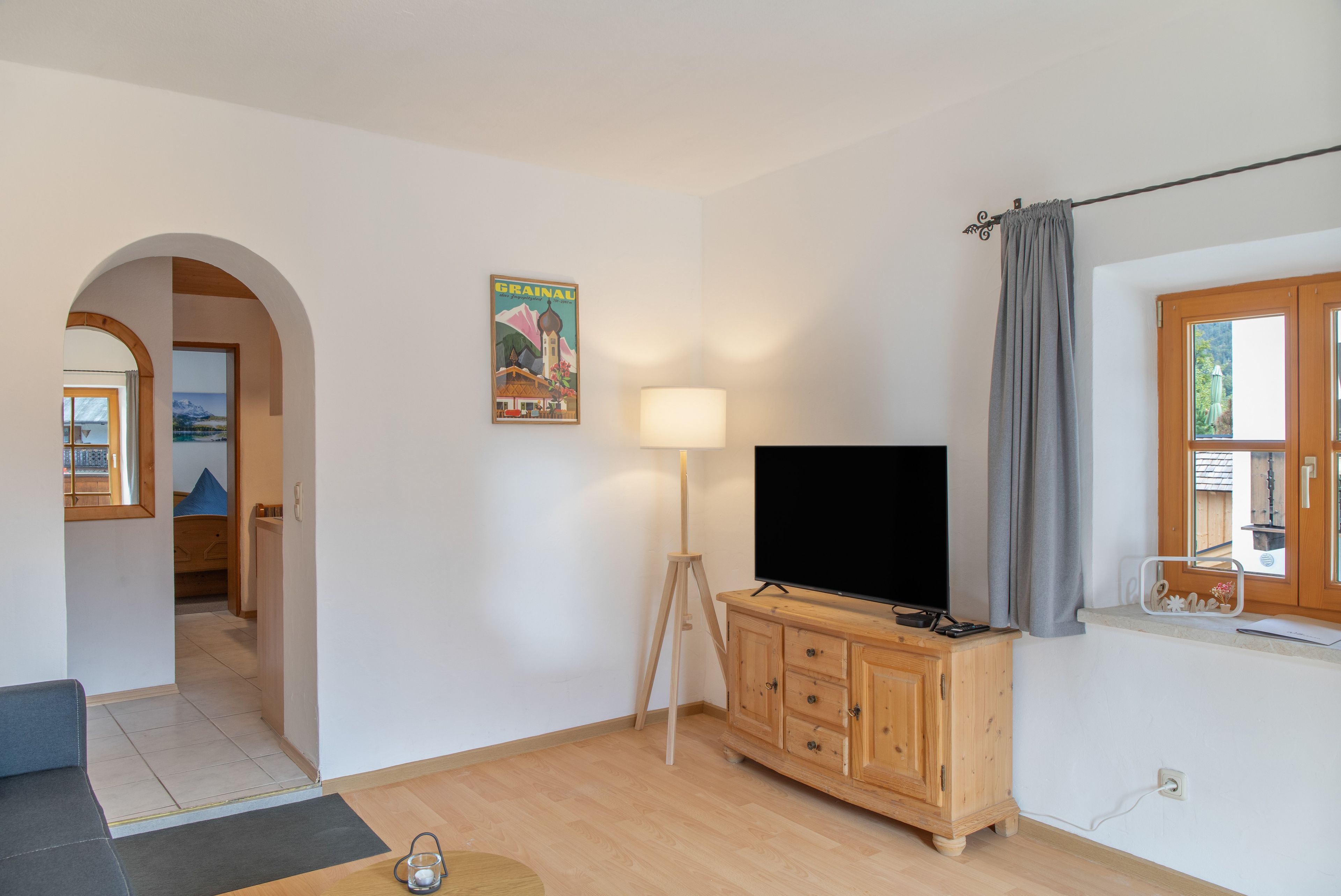 Ein Wohnzimmer mit Fernseher, Holzschrank und Lampe.