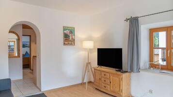 Ein Wohnzimmer mit Fernseher, Holzschrank und Lampe.