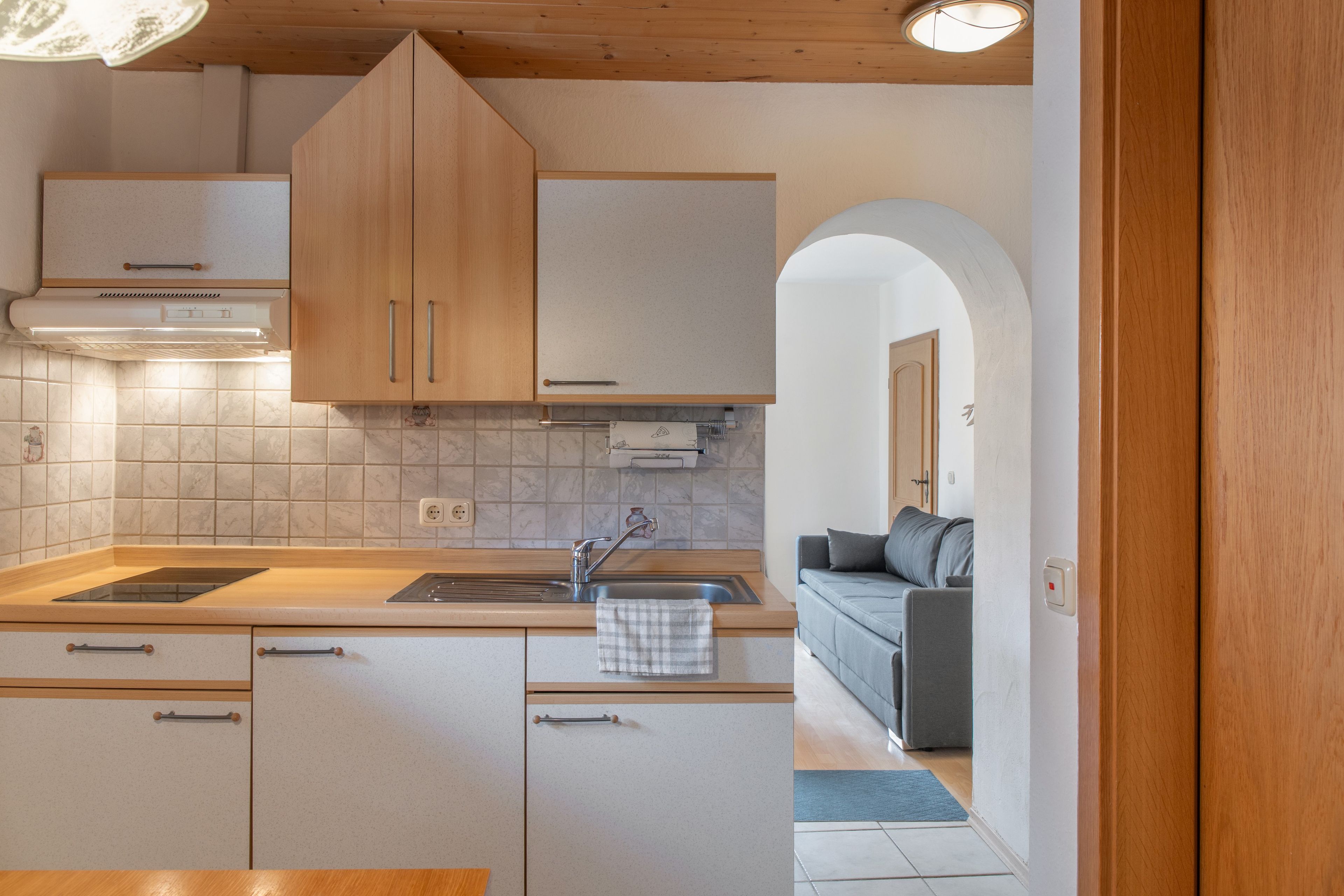 Una cocina compacta con armarios de madera, estufa integrada y un lavamanos.