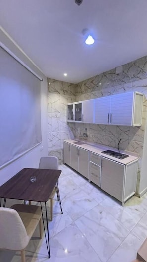 Una cocina compacta con armarios blancos, una encimera y un comedor con mesa y sillas.