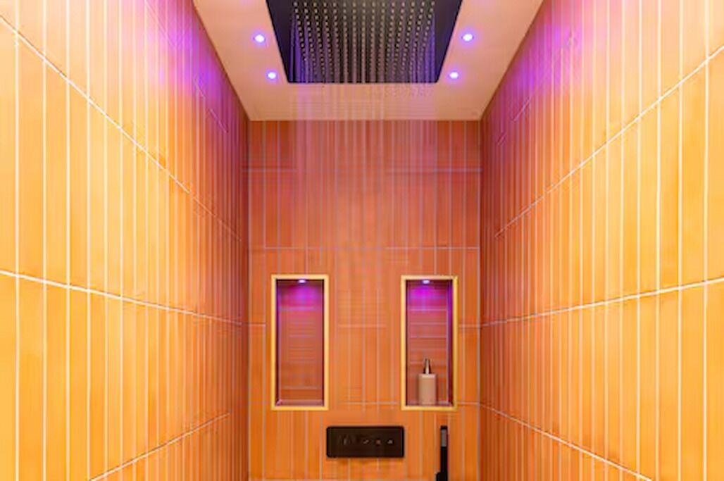 Une pièce avec un lambris vertical en bois, un luminaire au plafond et deux étagères fixées au mur, sur lesquelles sont posés divers objets.