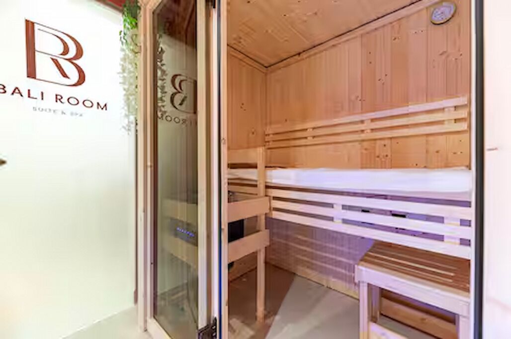 Een houten sauna met banken, een glazen deur en een logo op de muur.