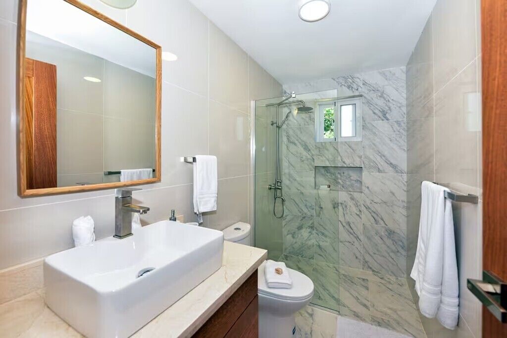 A modern bathroom with a large sink, toilet, and shower area.