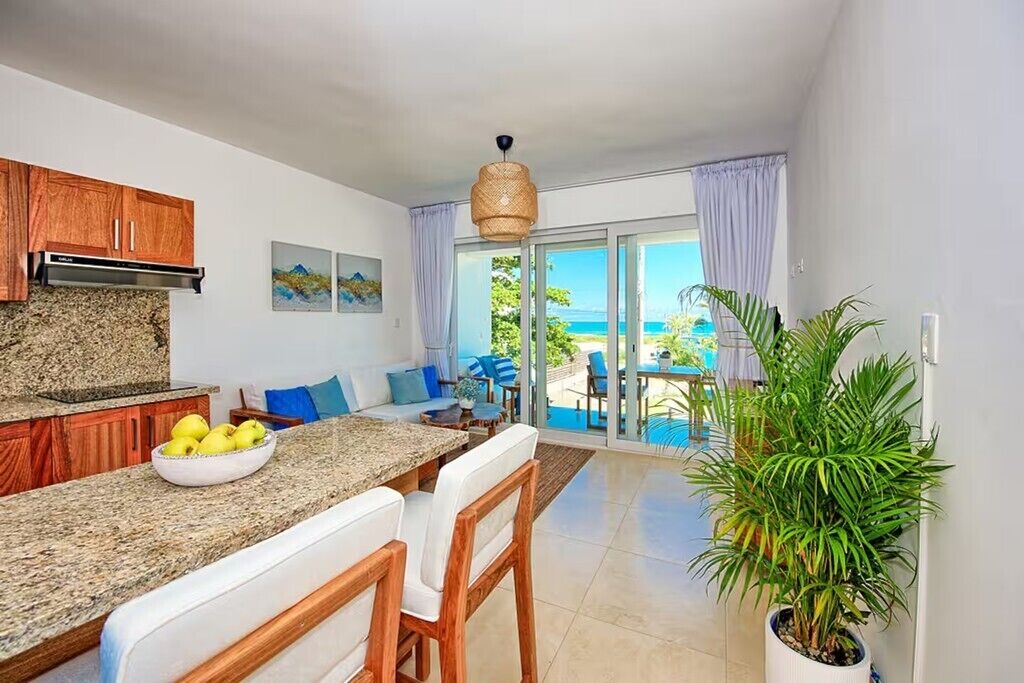 A modern kitchen with granite countertops, wooden cabinets, and a dining area with white chairs.