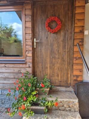 Eine Holztür mit einem Kranz, einem Fenster und einem Blumenbeet.