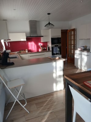 Eine moderne Küche mit Kochinsel, weißen Schränken und einer roten Spritzschutzwand.