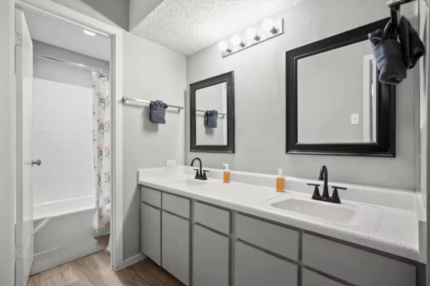 Une salle de bain avec un double lavabo, deux miroirs, un porte-serviettes et un rideau de douche.