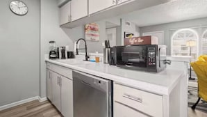 Eine moderne Küche mit Geschirrspüler, Kaffeemaschine und Mikrowelle.