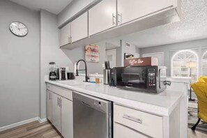 A modern kitchen with a dishwasher, a coffee maker, and a microwave. - Bright Stay • DT Austin • Pecan St. Festival Ready (Austin)
