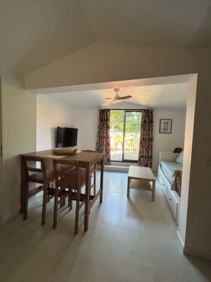 A room with a dining table, chairs, a TV, a bed, and a window with curtains. - One-bedroom cabin, shared pool (Six-Fours-les-Plages)