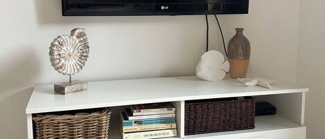 Un meuble de rangement blanc pour appareils électroniques, avec un téléviseur à écran plat fixé au-dessus.