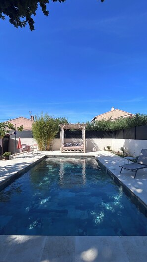 A swimming pool with a pergola seating area, surrounded by a patio with chairs and a table. - One-bedroom cabin, shared pool (Six-Fours-les-Plages)