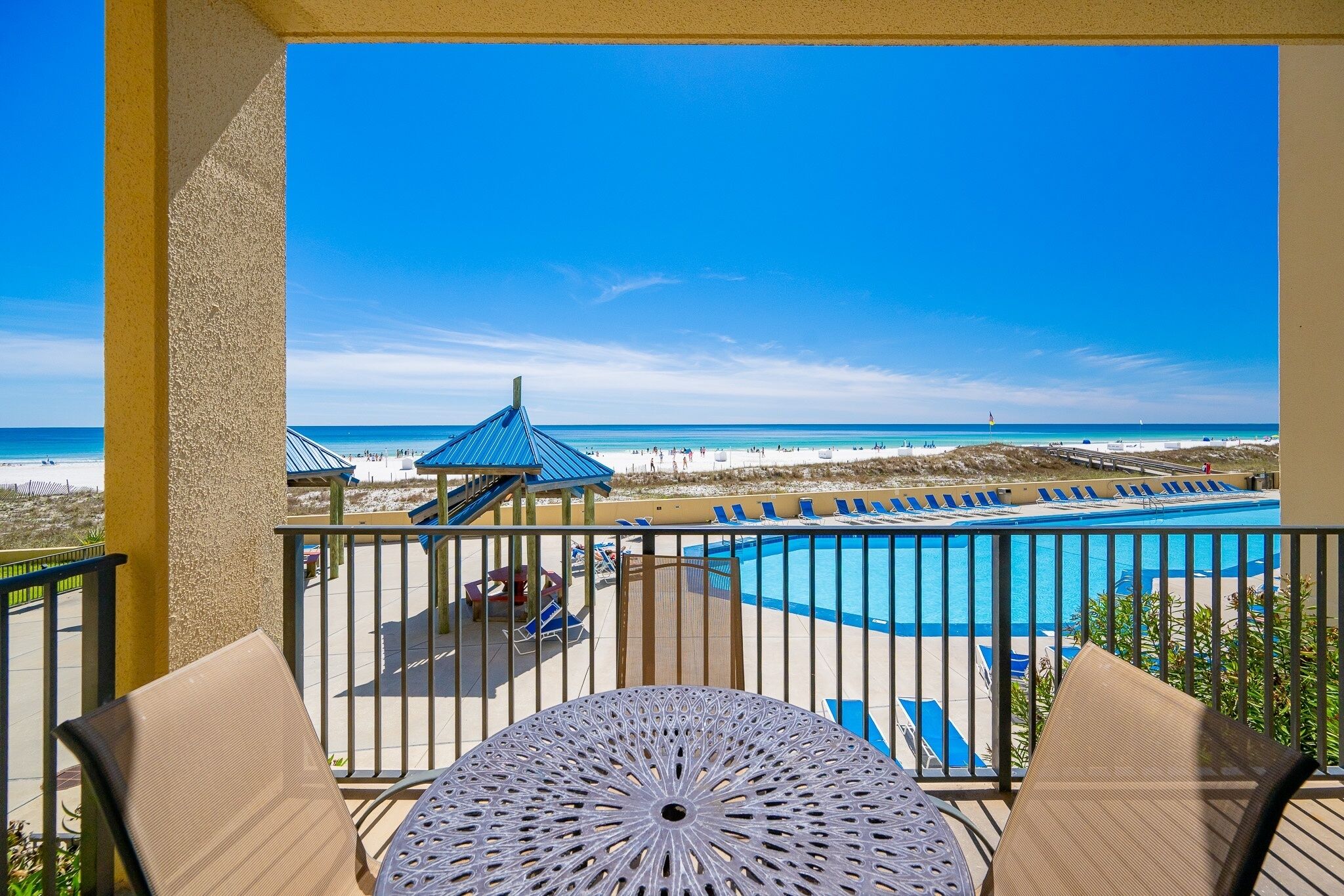 Un balcon avec vue sur une plage et une piscine.