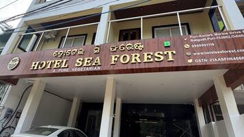 Een meerlaags gebouw met een bord waarop 'Hotel Sea Forest' staat, dat een vegetarisch restaurant aangeeft.