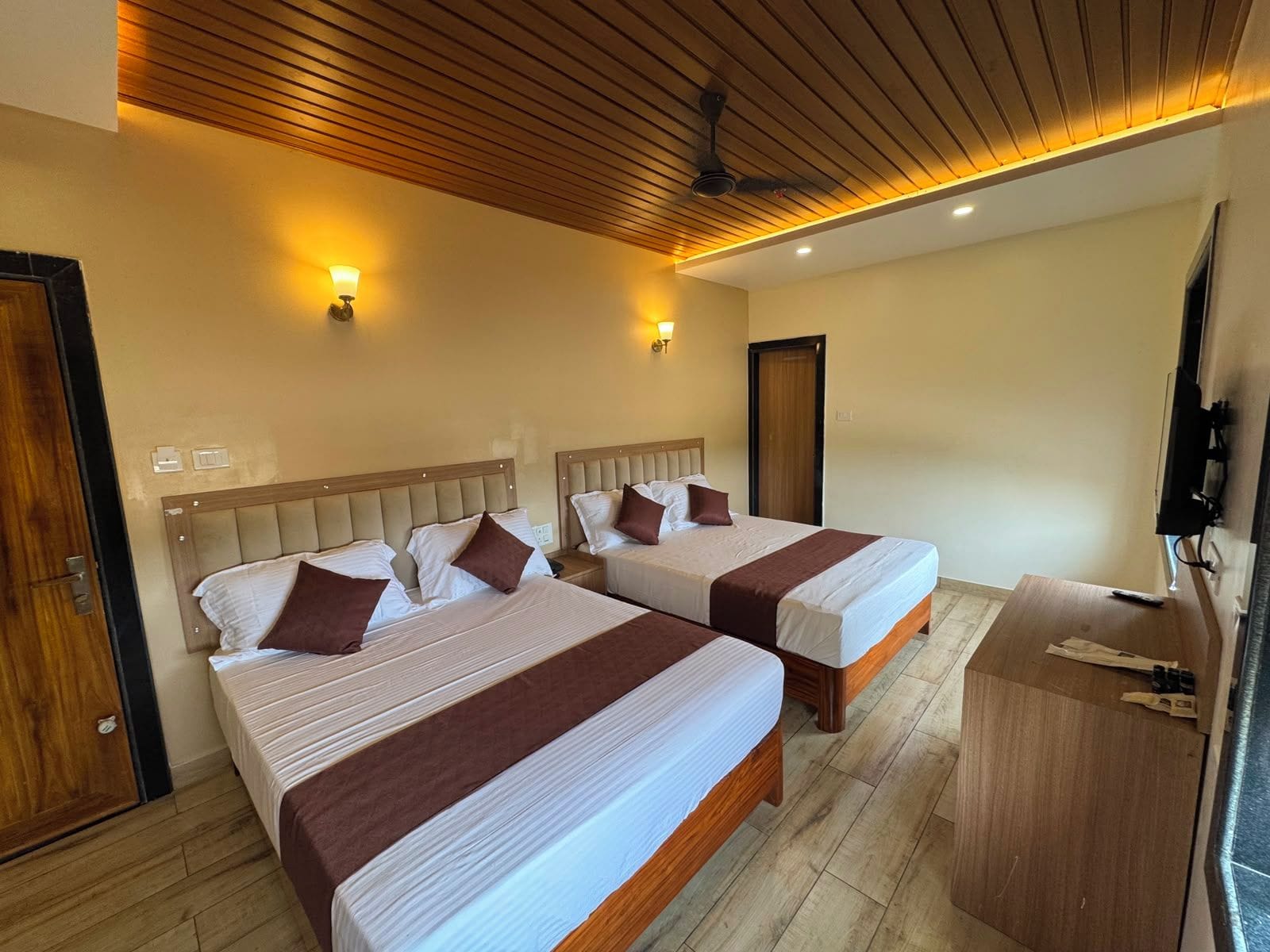 A hotel room with two beds, a wooden ceiling, and a TV on a wooden stand.