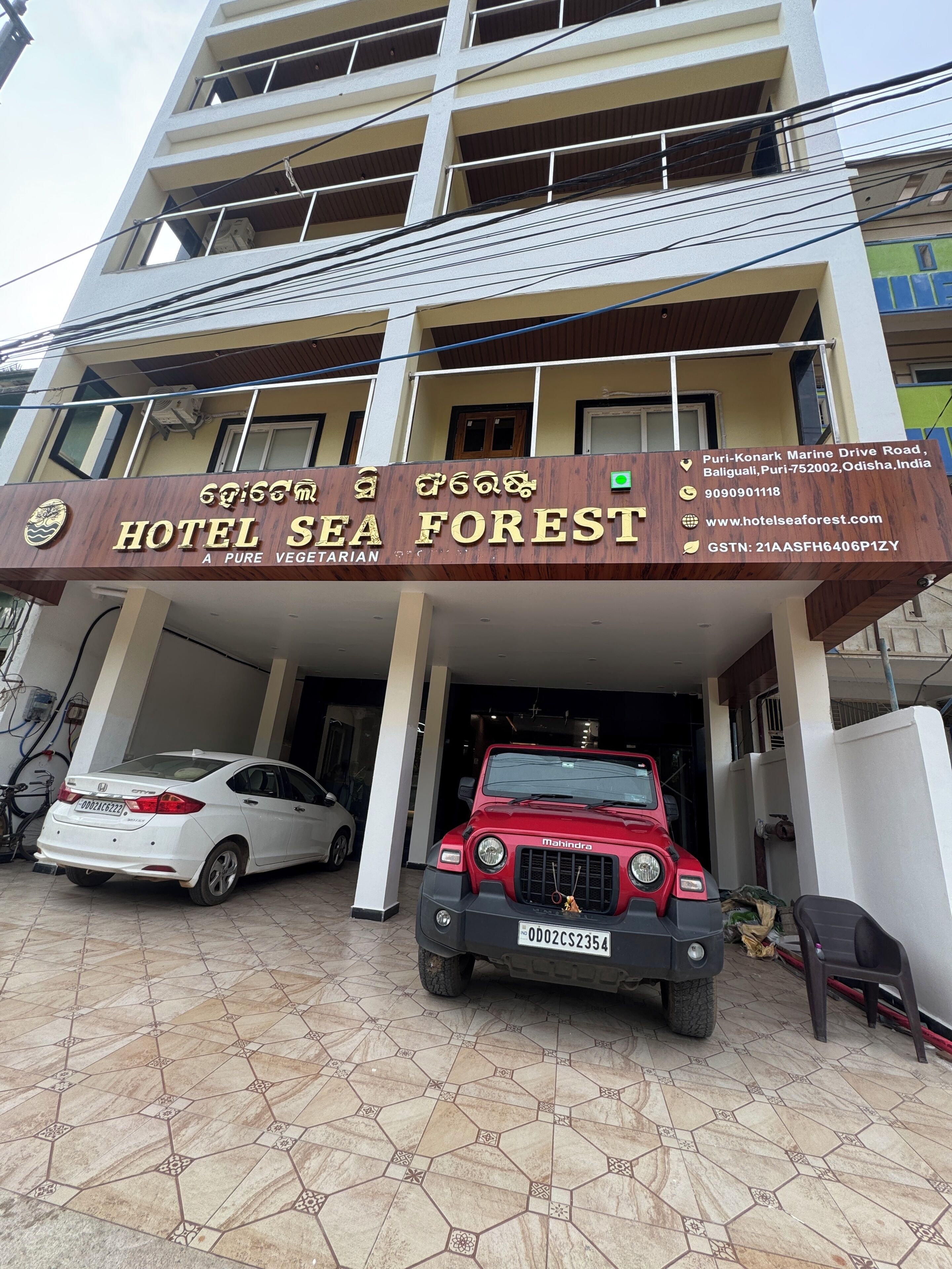 A hotel named 'Hotel Sea Forest' with a signboard displaying contact information and address.