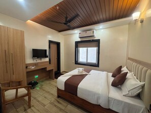 A bedroom with a bed, a television, a wardrobe, and an air conditioning unit. - Hotel Sea Forest (Puri)