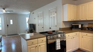 A kitchen with white cabinets, a black stove, and a microwave. - Charming Town home in “La Casita” at Haile. Safe, and Close to Everything (Gainesville)