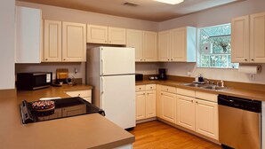 A kitchen with white cabinets, a refrigerator, a microwave, a dishwasher, and a window with a view of greenery. - Charming Town home in “La Casita” at Haile. Safe, and Close to Everything (Gainesville)
