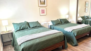 A hotel room with two beds, a nightstand with a lamp, a mirror, and framed pictures on the wall.