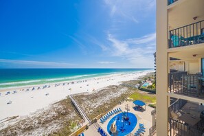 A beach view from a balcony with a pool and lounge chairs. - Phoenix V 709 2 Bedroom Condo (Orange Beach)
