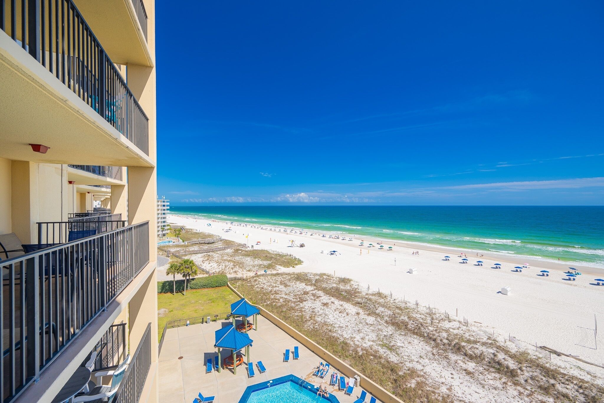 A hotel balcony with a view of a beach and a swimming pool.