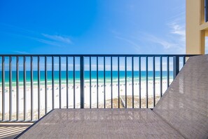 Een balkon met uitzicht op strand en zee.