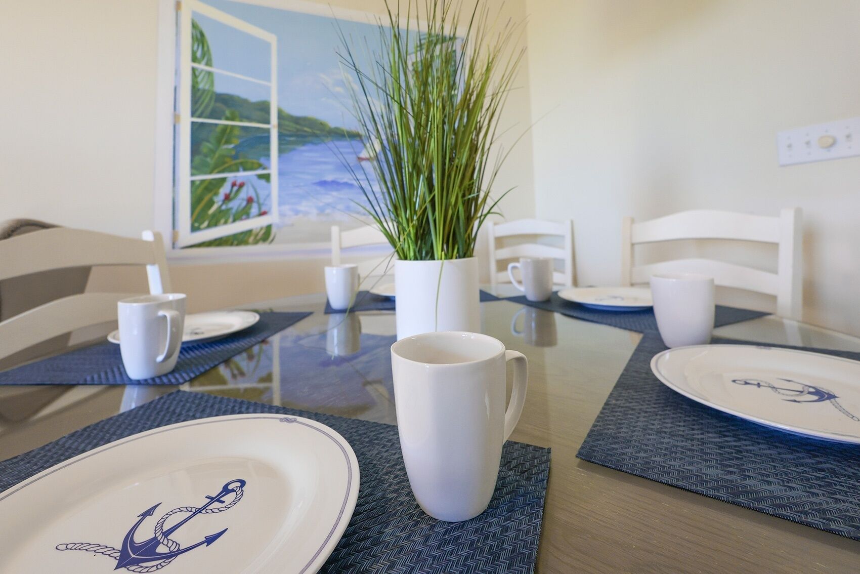 A dining table set with white plates, a white mug, and a potted plant.