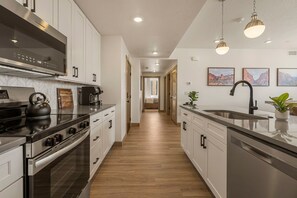 A modern kitchen with stainless steel appliances, wooden flooring, and pendant lighting. - Adventure Loft 3 Bedroom Condo (Hurricane)