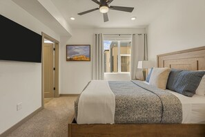 A hotel room with a bed, a television mounted on the wall, a ceiling fan, and a window with curtains. - Adventure Loft 3 Bedroom Condo (Hurricane)
